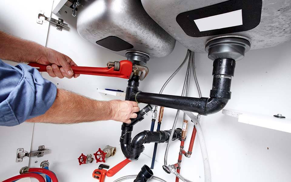 plumber fixing pipes under a sink